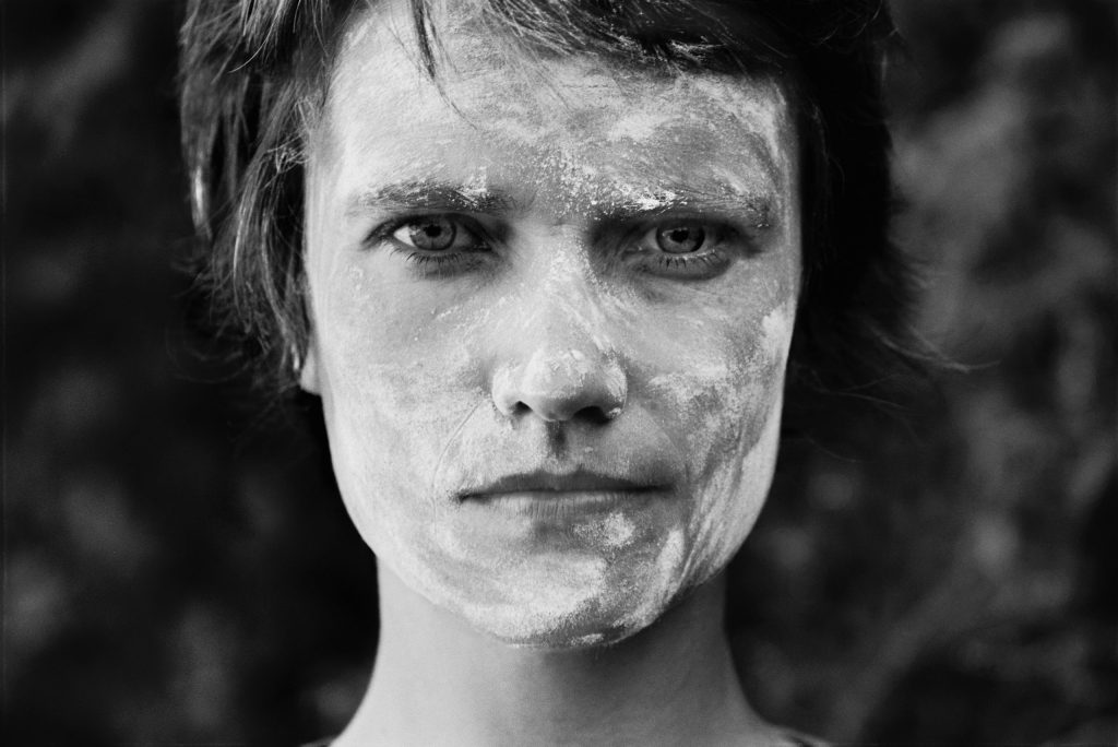 Zwart-wit portret van streng kijkende witte vrouw met donker haar en meel op haar gezicht als illustratie bij de leizng Het vrouwelijke in de man